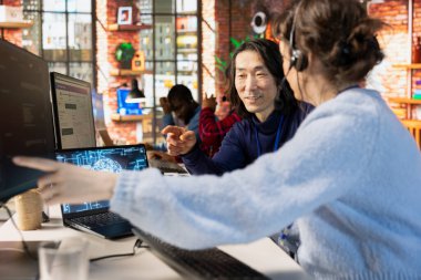 Gülümseyen Asyalı çağrı merkezi, yardımcı yapay zeka araçları üzerine çalışan yeni bir ajan yetiştiriyor. Müşteri destek bürosundaki arkadaş canlısı üst düzey yönetici, kadına şirket yapay zeka yazılımının nasıl kullanılacağını gösteriyor.