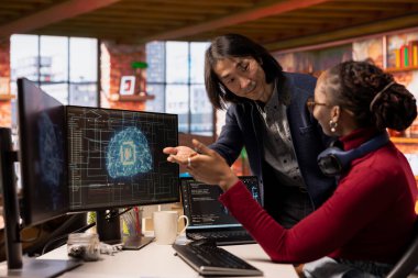 Çok ırklı başlangıç ofisindeki CTO yöneticisi ileri yapay zeka algoritması ve makine öğrenme modelleri kodlayan teknisyenlere yardımcı oluyor. Ekip lideri Silikon Vadisi 'ndeki işyerinde çalışanların yaptığı işleri denetliyor.