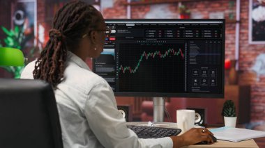 PC 'yi hisse senedi alıp satmak, dosya okumak, piyasa eğilimleri ve dalgalanmalardan yararlanmak için kullanan bir borsacı. Yatırımcı hisse senedi izleme eğilimleri bilgisayar monitöründe, kamera B