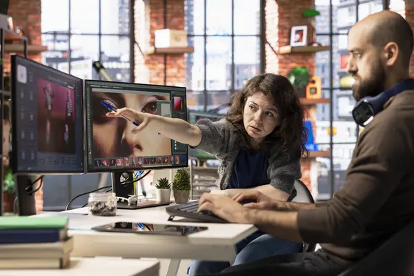 Profesyonel bir stüdyoda bir erkek ve bir kadın fotoğraf rötuşlaması için yapay zeka sistemi kullanıyorlar. Düzenleme yazılımı gelişmiş otomasyon uygular, çarpıcı görüntüler oluşturmada tasarımcılara yardımcı olur.