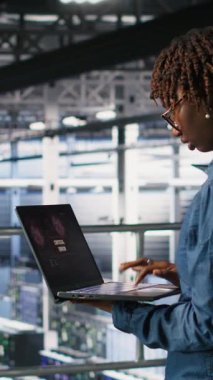 Dikey Veri Merkezi yazılım geliştiricisi dizüstü bilgisayarda kritik hata görüntüsü aldıktan sonra panikledi. Sunucu merkezindeki Afrikalı Amerikalı kadın düşük donanım performansına neden olan hatalar yüzünden alarma geçti