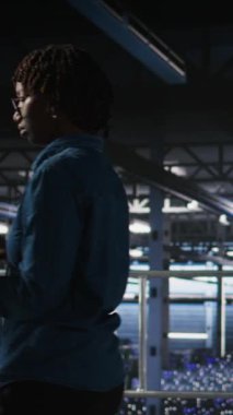 Endüstriyel platformda yürüyen dikey video veri merkezi mühendisi, hataları tespit etmek için ekipman üzerinde tarama yapıyor. Sunucu çiftliği bilişim uzmanları, platformların arıza süresini en aza indirmesini engelliyor