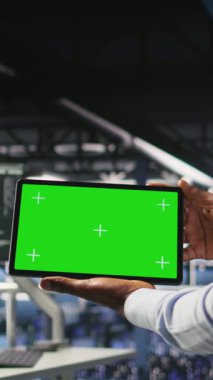 Bilişim uzmanlarının sinirsel ağ çıktılarını analiz etmek için kroma anahtar aygıtı kullandıkları dikey video. Veri merkezi yönetimi, meslektaşının yapay zekayı bulanıklaştırarak gözden geçirmesinin yanında yeşil ekran tableti kullanıyor