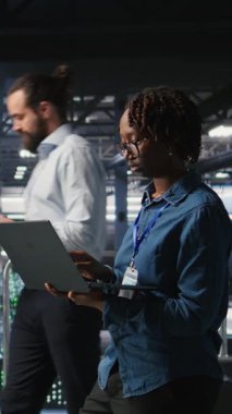 Veritabanı 'ndaki dikey video Mutlu kadın dizüstü bilgisayarda bakım görevleri yapıyor ve en iyi performansı sağlıyor. Mühendislik ekibi tanıları inceliyor ve sunucu odasına yama uyguluyor.