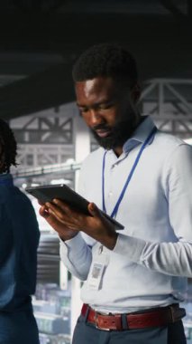 Veri merkezi endüstriyel platformunda yürüyen dikey video mühendisi sistem bakımını yapıyor. BT uzmanı, güncelleme yapmak, hataları çözmek ve altyapı istikrarını artırmak için tablet kullanıyor