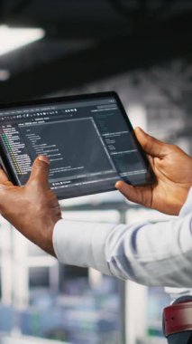 Tablet üzerinde çalışan kod ayıklama araçlarına bakan veri merkezi programcısının dikey videosu. Sunucu çiftliği IT profesyonel kontrol makinesi otomatik betik öğrenme görevleri, kamera B