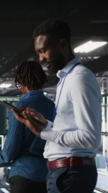 Dikey video teknisyeni veri merkezinde yürüyor, tablet üzerinde bakım görevleri yapıyor, en iyi performansı sağlıyor. Bilişim uzmanı tanıları inceliyor ve sunucu merkezi dişlilerine yama uyguluyor, geliştiriyor