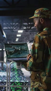 Sunucu odasındaki dikey video askeri, acil operasyonlar sırasında tahliye için coğrafi verileri kullanır. Afet müdahale lojistiğini koordine eden üniformalı askeri veri merkezi personeli