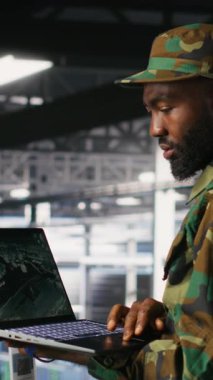 Veri merkezindeki dikey video askeri teknisyeni bilgisayardaki savaş uzaktan kumandalı uzaktan kumanda ölçümlerini izliyor. Ordu sunucu odasında bilgi işlem uzmanı. Hava desteğini sağlamak için dizüstü bilgisayarda taktik arayüzü kullanıyor.