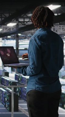 Dikey Veri Merkezi yazılım geliştiricisi dizüstü bilgisayarda kritik hata görüntüsü aldıktan sonra panikledi. Sunucu merkezindeki Afrikalı Amerikalı kadın düşük donanım performansına neden olan hatalar yüzünden alarma geçti