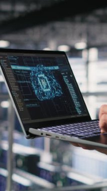 BT uzmanının sunucu odasında yapay zeka öğrenme otomatikleştirmesi yapan dikey videosu. Not defteri kullanarak veri merkezi yazılım geliştiricisi, donanım bakımını AI, kamera B kullanarak yapıyor