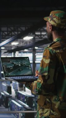 Veri merkezindeki dikey video askeri teknisyeni bilgisayardaki savaş uzaktan kumandalı uzaktan kumanda ölçümlerini izliyor. Ordu sunucu odasında bilgi işlem uzmanı. Hava desteğini sağlamak için dizüstü bilgisayarda taktik arayüzü kullanıyor.