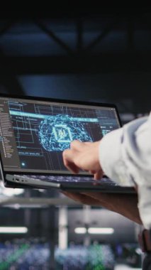 BT uzmanının sunucu odasında yapay zeka öğrenme otomatikleştirmesi yapan dikey videosu. Veri merkezi yazılım geliştiricisi, defter kullanarak donanım bakımı yapıyor. Yapay zeka, kamera A kullanarak.
