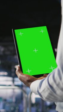 Yeşil ekran model tableti kullanan dikey video veri merkezi çalışanı, yapay zeka görevleriyle ilgilenen tırların bakımını yapıyor. Derin depolama dizilerini desteklemek için krom anahtar aygıtı kullanan sunucu merkezi yönetimi