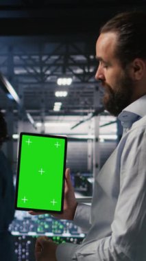 Yüksek teknoloji sunucu tesislerindeki izole ekran tabletindeki yapay zeka işlemlerini denetleyen dikey video askeri personeli. Ordu teknoloji uzmanları iletişim sistemlerini denetlemek için krom anahtar aygıt kullanıyorlar.