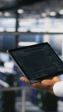 Dikey video, veri merkezi yönetimini makine öğrenme kod gösterge panellerini incelemek için tablet kullanarak kapat. Yapay zeka altyapı performansını izlemek için aygıt kullanan sunucu çiftliği bilişim uzmanı, kamera B