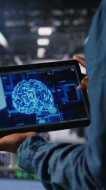 Sunucu çiftlik yönetiminin dikey videosu. Tablet kullanarak altyapı yapay zeka öğrenme otomatikleştirmesi yapılıyor. Veri Merkezi yazılım geliştiricisi yapay zeka kullanarak bakım yapıyor