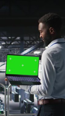 Endüstriyel platformdaki dikey video veri merkezi programcıları yeşil ekran dizüstü bilgisayar kullanarak görevlerde işbirliği yapıyorlar. Sunucu merkezi çalışanları büyük dil model mimarisini maket defter kullanarak görselleştiriyor