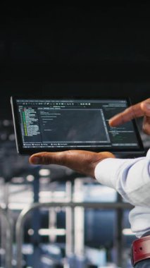 Veritabanında tablet görüntülemede kaydırma yapan programcının dikey videosu, bakım görevleri yapmak, en iyi performansı sağlamak. IT uzmanı aygıt üzerindeki kodu kontrol ediyor, geliştirmek için yamalar uyguluyor
