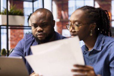 Rapor kağıtlarından veri girerek hesap tablolarını dolduran çift ay sonunda toplam rakamları hesaplıyor ve analiz ediyor. Evden çalışan Afrikalı Amerikalılar..