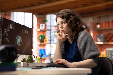 Ofisteki genç şirket analisti bilgisayar ekranında iş sunumunu izliyor, istatistik tablolarını ve performans ölçümlerini inceliyor. Çalışan bilgisayardaki sunum grafiklerine bakıyor.