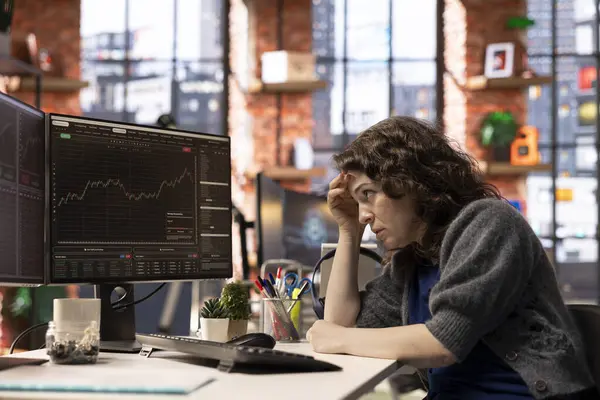 Borsacı endişeli ve stresli bir şekilde maddi kayıplara bakıyor, bilgisayardaki hisse senedi fiyatlarını analiz ediyor. Öfkeli kadın hisselerini kaybediyor ve piyasa çöküşü ile uğraşıyor..