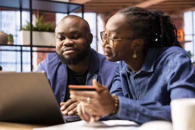 Olgun bir çift online bankacılık ve kredi kartı ile ödemeleri yönetiyor, para transferini onaylamak için bir web sitesine numaralarını giriyorlar. Merkez ofisteki sıradan insanlar alım satım yapıyor..