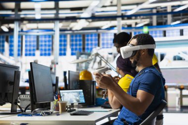 Fotovoltaik tesisi uzmanı alternatif enerji jeneratörlerinin modellerini yapmak için VR teknolojisini kullanıyor. Güneş panelleri fabrika erkek çalışanı sanal gerçeklik teçhizatı kullanarak güvenli güneş hücreleri inşa ediyor.