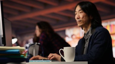 Yenilikçi başlangıç ofisinde çalışan kıdemli yönetici uygulama oluşturmak için programlama dilleri kullanıyor. Deneyimli yazılım geliştirme ajansı IT CTO denetleyicisi bilgisayardaki kodu optimize ediyor, kamera B