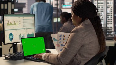 Şirket çalışanı yeşil ekranın yanındaki stratejik planlama üzerine odaklanarak iş amaçlarına ulaştı. Kadın danışman bütçe analizi ve performans ölçümleriyle ilgileniyor. Kamera A.
