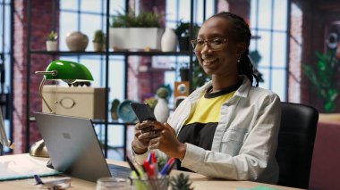 Cep telefonundan mesaj okuyan neşeli insan portresi, iyi haberler aldıktan sonra sevindi. Samimi bir dairede neşeli bir kadın akıllı telefondaki SMS ile heyecanlanıyor, arkadaşlarıyla sohbet ediyor, kamera B