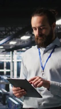 Nöral ağ kodunu ve LLM görselleştirme panellerini inceleyen iş arkadaşlarının yanındaki dikey video sunucu odası teknisyeni. Veri Merkezi Bilişim Uzmanı YZ sistem performansını izleyen meslektaşlarının yanında