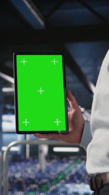 Veritabanı yöneticisinin dikey videosu depolama dizilerini güncellemek için tablet kullanarak ağ viralizasyonunu yapılandırıyor. Sunucu odası bilişim uzmanı ayarları doğrulamak için krom anahtar aygıtı kullanıyor