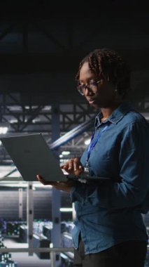 Veri merkezindeki neşeli bilgisayar bilimcisinin dikey video portresi sinirsel ağ LLM görselleştirmesini izliyor. Sunucu çiftliğindeki neşeli kadın teçhizata güç veren makine öğrenme süreçlerini denetliyor, kamera