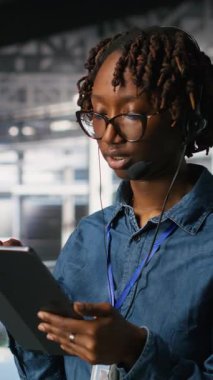 Tablet ve kulaklık kullanarak altyapı teknik desteği sağlayan dikey video sunucu odası yönetimi. Veri merkezi bilişim uzmanı uzak ekiplerle koordine ederken arka uç sorunlarını çözer