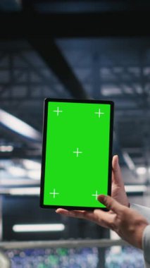 Yüksek teknoloji sunucu tesislerindeki izole ekran tabletindeki yapay zeka işlemlerini denetleyen dikey video askeri personeli. Ordu teknoloji uzmanları iletişim sistemlerini denetlemek için krom anahtar aygıt kullanıyorlar.
