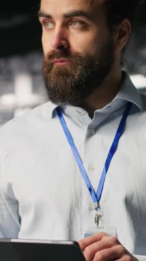 Dikey video Keyifli Veri Merkezi Yöneticisi tablet üzerinde bakım görevleri yapıyor ve en iyi performansı sağlıyor. Bilgi İşlem uzmanının sunucu merkezi dişlisine yama uygulaması ve teşhisi gözden geçirmesi