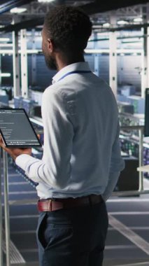 Dikey video veri merkezi programcısı kod satırlarını kontrol ediyor ve iş arkadaşı AI LLM görselleştirmelerini inceliyor. Bilişim uzmanları, istikrarlı altyapı operasyonlarını sağlamak için nöral ağ çıktılarını analiz ederler