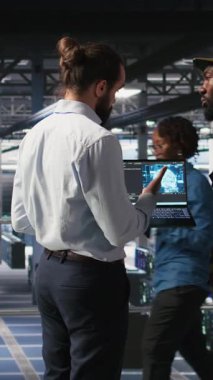 Komuta merkezindeki sunucu odasında dikey video teknisyenleri siber tehditleri tespit etmek için yapay zeka kullanıyorlar. Askeri veri merkezi uzmanları savunma sistemlerini korumak için yapay zeka tespit yazılımı kullanıyorlar