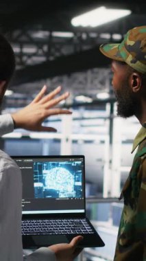 Güvenli veri merkezindeki dikey video teknisyenleri yapay zeka sistemlerini izlemek için dizüstü bilgisayar kullanıyorlar. Ordu operatörleri sunucu merkezinde makine öğrenimi için istikrarlı altyapı sağlıyorlar