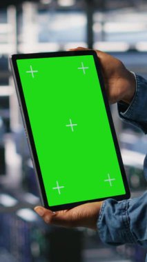 Yeşil ekran model tableti kullanan dikey video veri merkezi çalışanı, yapay zeka görevleriyle ilgilenen tırların bakımını yapıyor. Derin depolama dizilerini desteklemek için krom anahtar aygıtı kullanan sunucu merkezi yönetimi