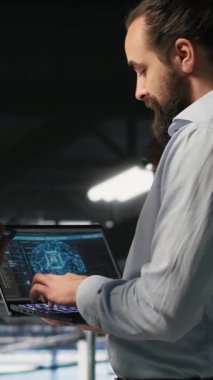 Dikey Veri Merkezi ekip lideri ve AI ekipman platformlarının performans gösterge panellerini inceleyen işçi. Sunucu odası denetleyicisi, programcının ekrandaki inceleme makinesi öğrenme algoritmalarını denetler