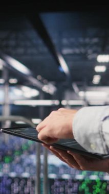 Tablet üzerinde bakım görevleri yapan veri merkezi yazılım geliştiricisinin dikey videosu en iyi performansı sağlıyor. İşçi tanıları gözden geçiriyor ve sunucu merkez ekipmanlarına yama uyguluyor