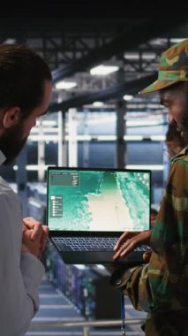 Askeri veri merkezindeki dikey video operatörleri dizüstü bilgisayar arayüzü ile otonom uçuş sistemlerini denetliyor. Ekip çalışması bilişim uzmanları canlı İHA takibi yapıyorlar. Not defteri, kamera A kullanarak.