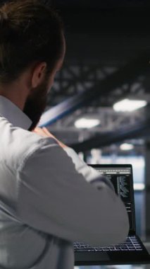 Yüksek teknoloji sunucu tesisinde yapay zeka hesaplama operasyonlarını gözetleyen dikey video askeri birimleri. Ordu teknoloji uzmanları iletişim sistemlerini denetlemek için makine öğrenme zekası kullanıyorlar.
