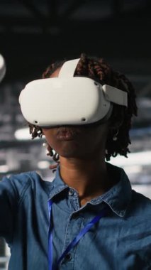 Sanal gerçeklik teknolojisini kullanarak yapay zeka sinirsel ağlarını simüle eden dikey video veri merkezi programcısı. Sunucu çiftliğindeki kadın AI sistemlerini denetlemek için VR kulaklık kullanıyor.