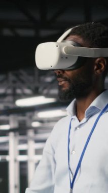 Sinirsel ağ AI sistemlerini izlemek için VR kulaklık kullanan dikey video veri merkezi yöneticisiName Sunucu odası çalışanı sanal gerçeklik teknolojisini kullanarak makine öğrenme süreçlerini denetliyor.