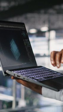 Dikey video sunucusu merkez çalışanları not defteri kullanarak büyük dil model mimarisini görselleştiriyorlar. Veri merkezi teknisyenleri endüstriyel platformda nöral ağ yazılım görevlerinde işbirliği yapıyorlar.