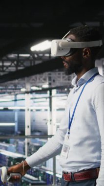 Sinirsel ağ AI sistemlerini izlemek için VR kulaklık kullanan dikey video veri merkezi yöneticisiName Sunucu odası çalışanı sanal gerçeklik teknolojisini kullanarak makine öğrenme süreçlerini denetliyor.