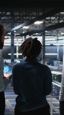 Dikey Veri Merkezi Yöneticisi, yapay zeka için kullanılan süper bilgisayarlarda bakım yapan işçilerle konuşuyor. Sunucu merkezi ekip lideri ve personel üyeleri derin öğrenme eğitimi için kullanılan platformları güncelliyor